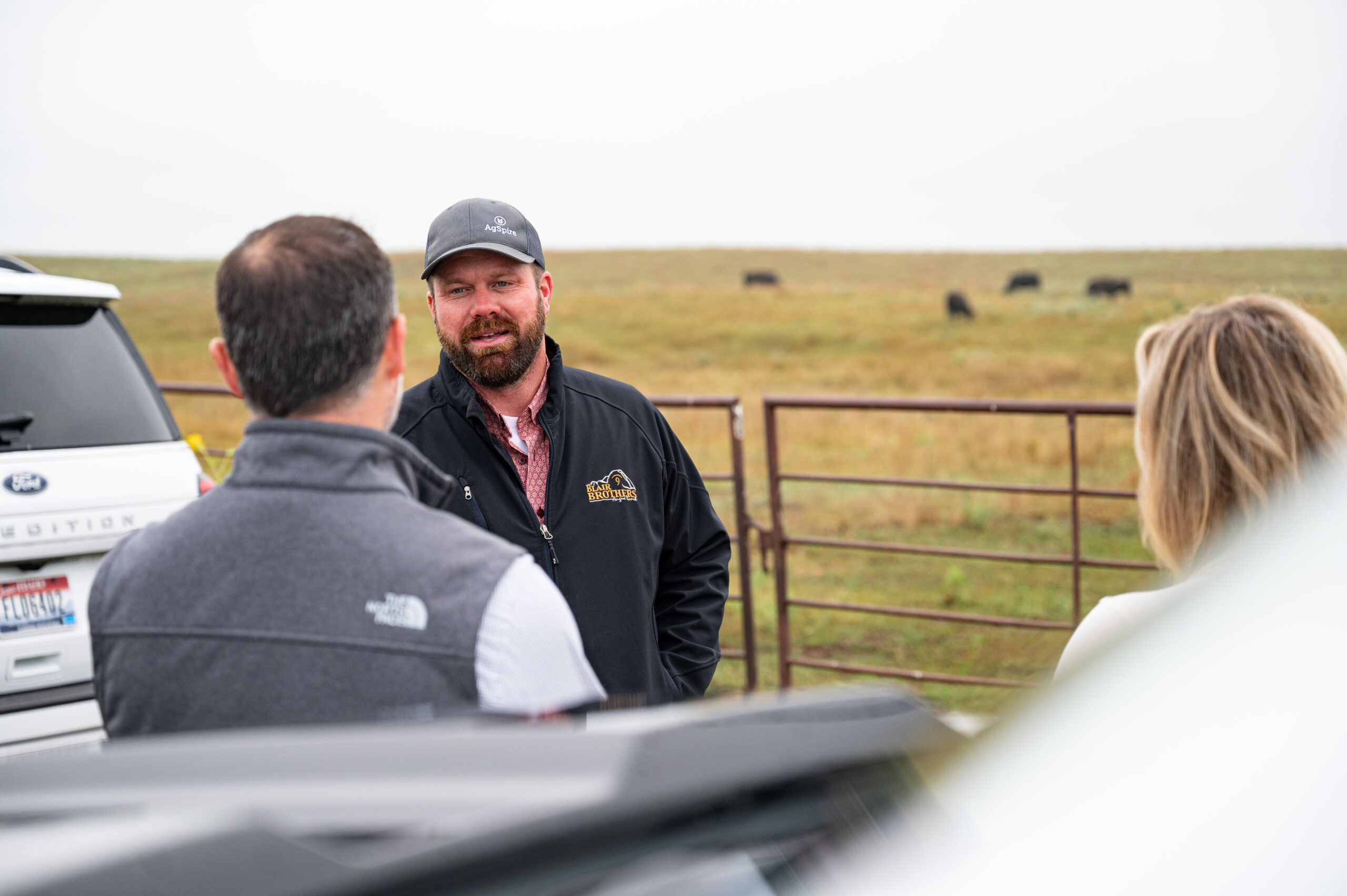 Farmer talking to another farmer in a pasture of green grass. AgSpire serves as your partner to promote a more resilient and profitable future. 